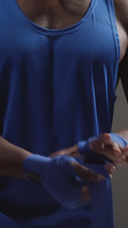 vertical video close up of male boxer wrapping hands with protective bandages before boxing match or training session