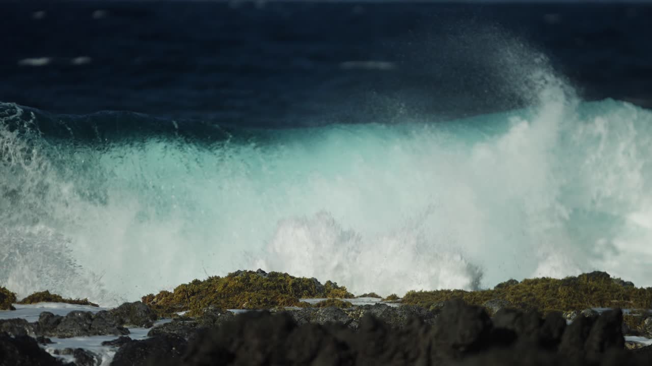 tomada en cámara lenta de fuertes olas oceánicas inundando rocas de lava en la costa de hawai