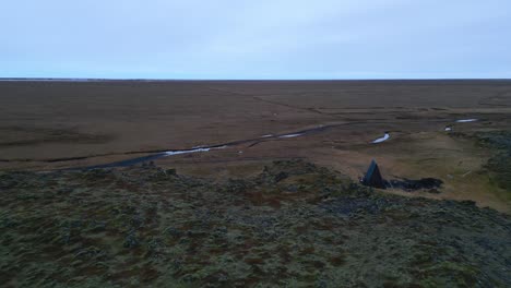 small wooden shelter in barren desolated landscape aerial establishing