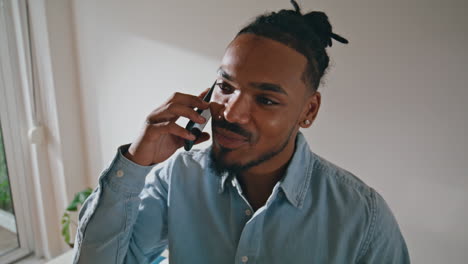 smiling guy talk smartphone at remote workplace. man cellphone conversation home