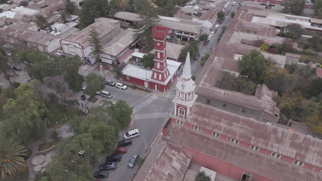 spiral drone shot around the town of vicuña near coquimbo in chile south america with the main square and red tower torre bauer visible on a grey day with mountains in the background log