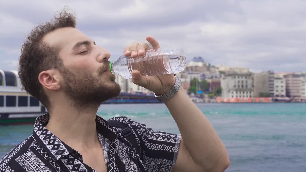 el hombre bebiendo agua junto al mar en estambul.