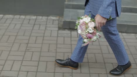 Groom-walking-to-his-bride-holding-wedding-bouquet-in-hand.-Slow-motion