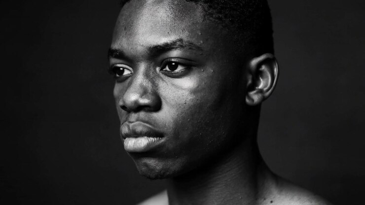 Hombre sin camiseta moviéndose, girando la cabeza y la mirada en un estudio, mientras la cámara filma un primer plano, con un fondo oscuro.