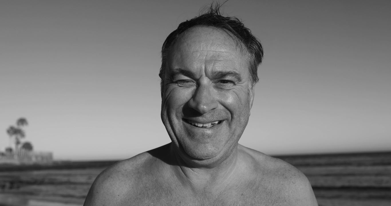 Uomo sorridente sulla spiaggia in bianco e nero
