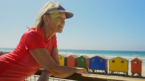 Side-view-of-active-senior-Caucasian-woman-standing-on-a-promenade-at-beach-4k