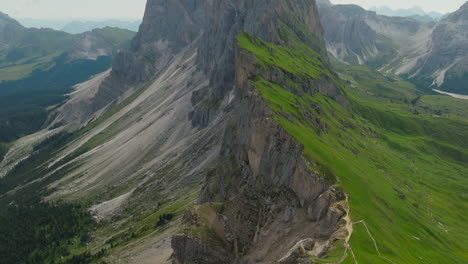 slow drone reveal shot of seceda ridgeline in dolomites, italy during spring