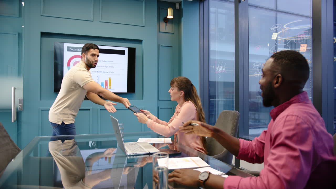 Presenting department reports, man pointing at screen while diverse colleagues discuss in office mee