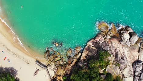 Beautiful-secluded-sandy-beach-with-turquoise-water-surrounded-by-rocks-and-stones