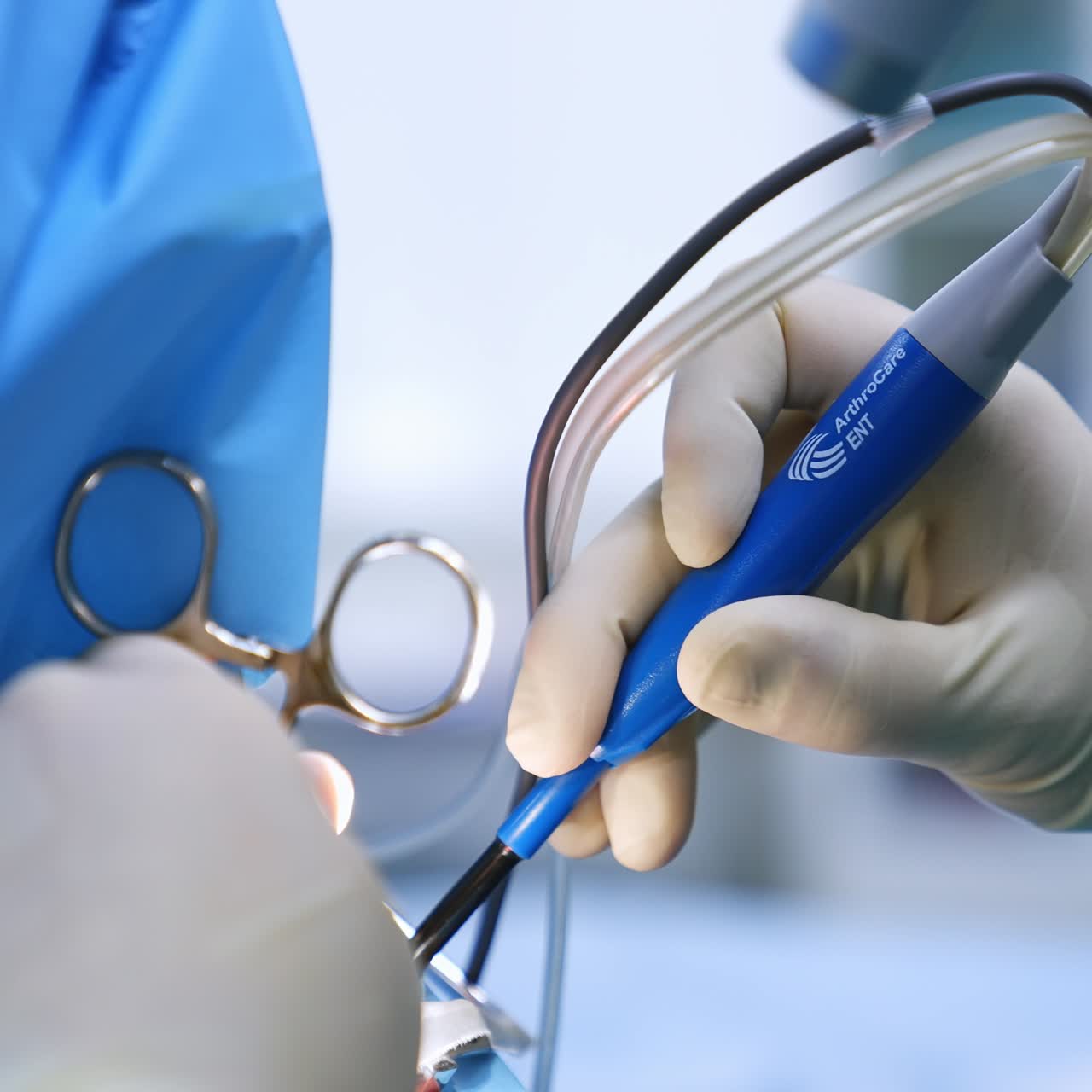 Doctor manipulating with the modern electric device for otorhinolaryngology surgery. Surgeon holding instruments in both hands at operation. Close up