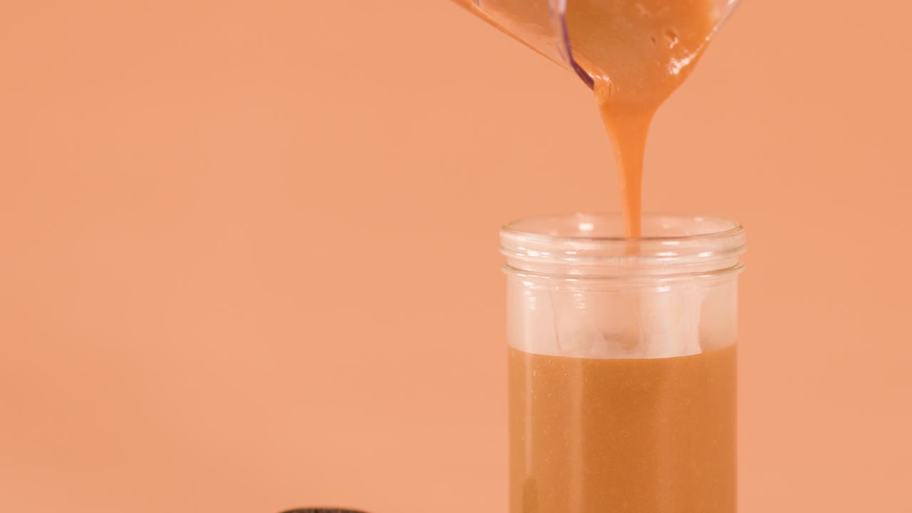 Bevanda al cioccolato versata da un frullatore in un barattolo di vetro, circondata da cookie e barrette di cioccolato