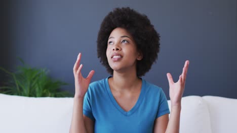 Portrait-of-african-american-woman-talking-on-videocall-while-sitting-on-the-couch-at-home