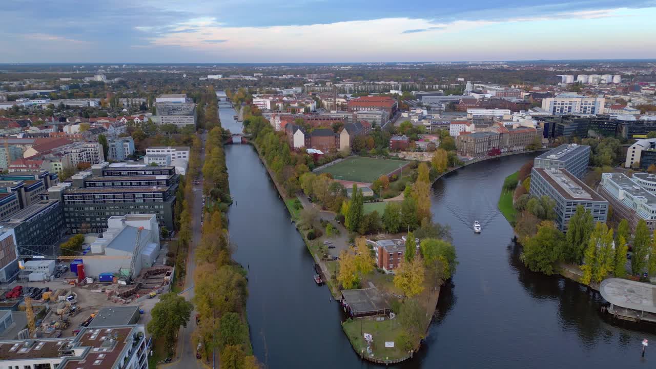 Berlin cityscape featuring a river, urban buildings, and a soccer field during autumn. Magic aerial view flight panorama overview drone