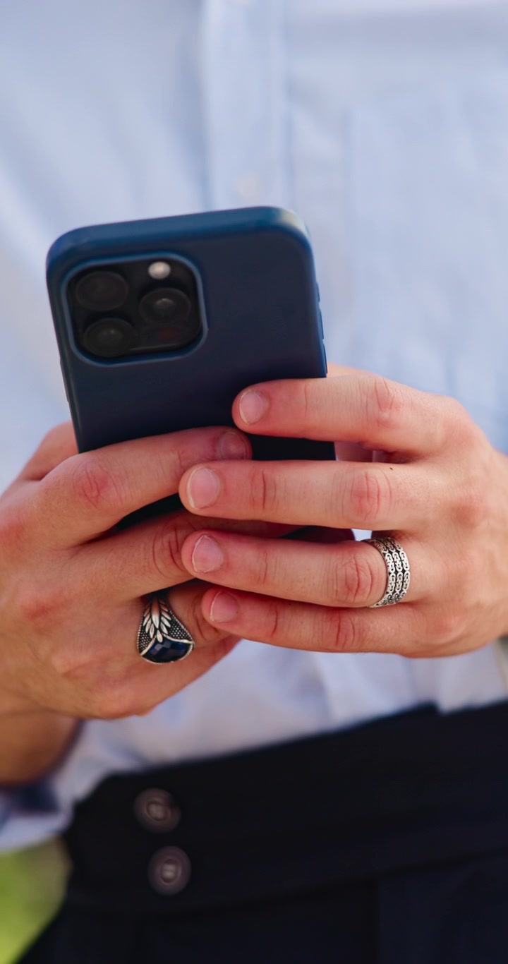 Primo Piano di un Uomo che Usa lo Smartphone con Anelli Eleganti