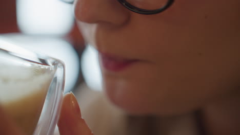 extreme close up of woman gently holding milkshake with both hands near lips as she prepares to sip, soft natural lighting and bokeh blur in background