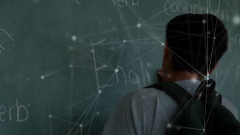 animation of network of connections over biracial schoolboy writing on chalkboard