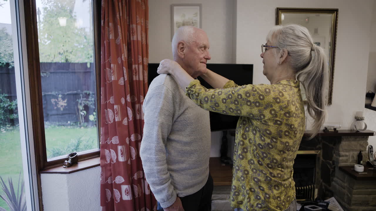 Elderly couple indoors helping each other