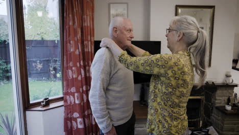 elderly couple indoors helping each other