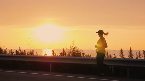 silhouette of a woman who runs along the road along the sea at sunset active middle aged people