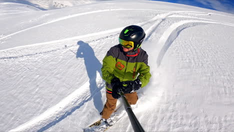 happy snowboarder in helmet goes down the mountain slope taking selfie video. active time spending in the nature in winter.