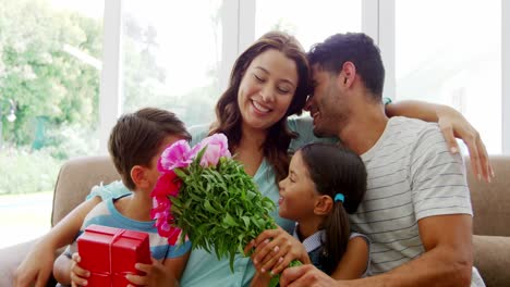 Glückliche-Familie-Sitzt-Auf-Dem-Sofa-Und-Umarmt-Sich-Im-Wohnzimmer