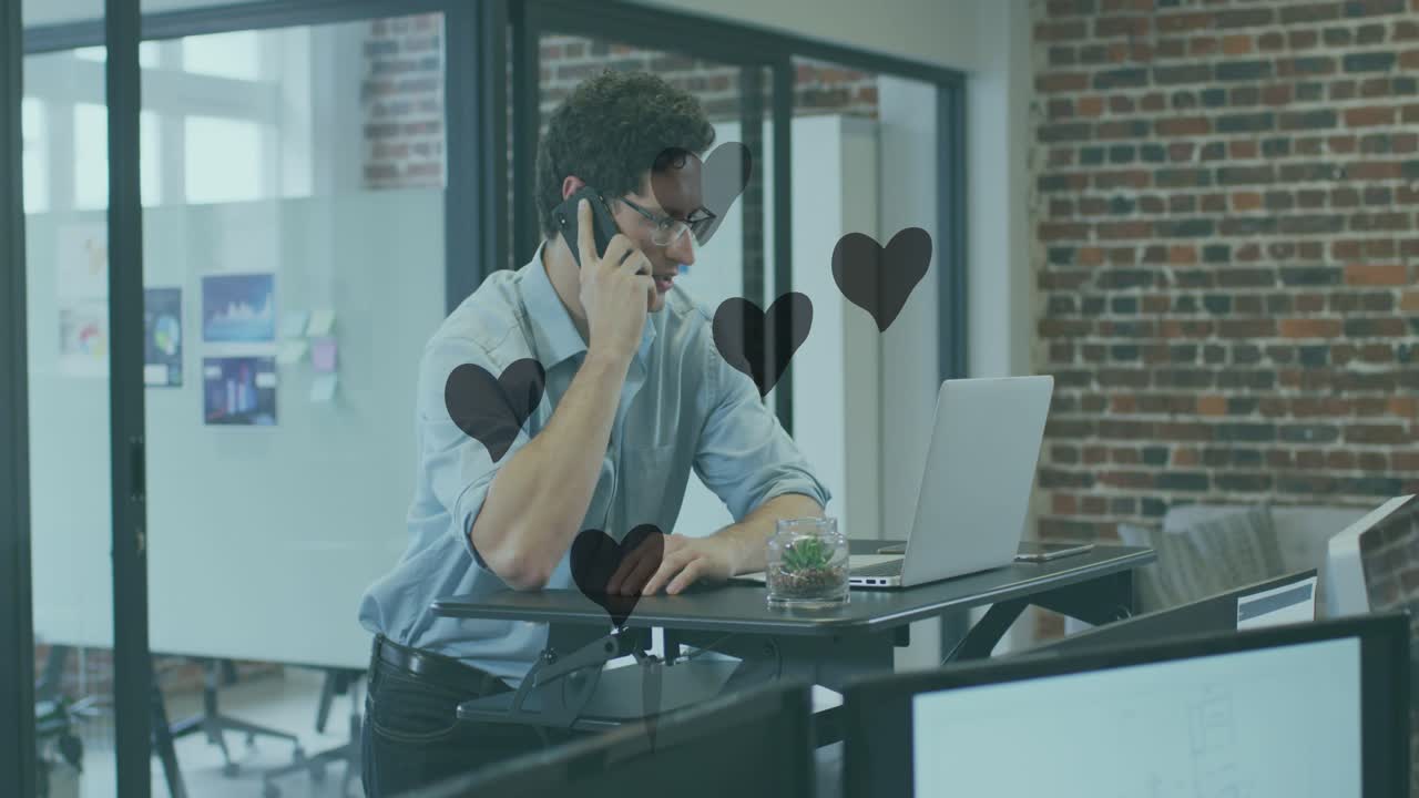 Animation af hjerter, der svæver over en kaukasisk forretningsmand, der taler i telefon på kontoret.