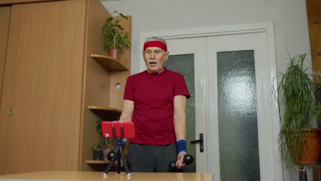 Old-senior-grandfather-man-doing-workout-with-dumbbells,-training,-fitness,-sport-activity-at-home