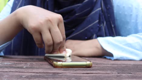 mujeres limpiando las manos de la pantalla del teléfono móvil para prevenir el virus