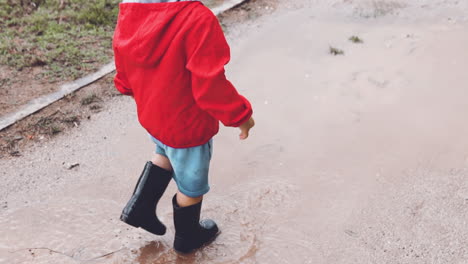 niño caminando a cámara lenta en un charco fangoso en el parque