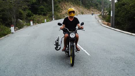 view of vietnamese motorcyclist transporting black kiteboard on the road in vietnam