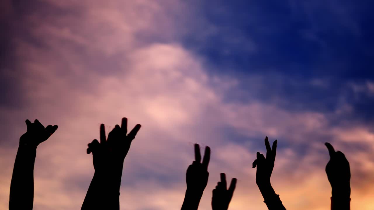 Silhouetted hands against a colorful sky