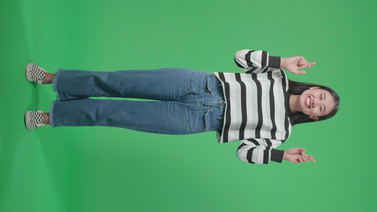 Woman in casual clothing, fingers crossed, against a green screen