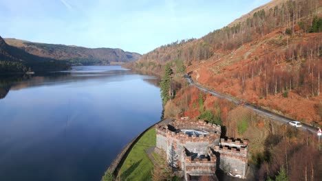 lakeside road with light traffic and castle-like structure next to reservoir