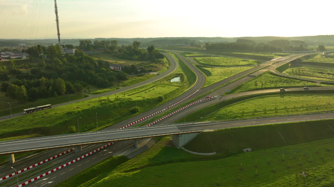 Sunlit aerial view of modern overpass and interchange with greenery and rolling hills