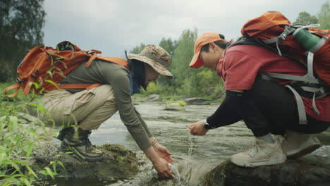asian female tourists washing hands in river