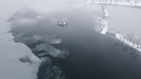 Drone-shot-of-winter-scene-with-birds-on-the-iced-surface-of-frozen-river