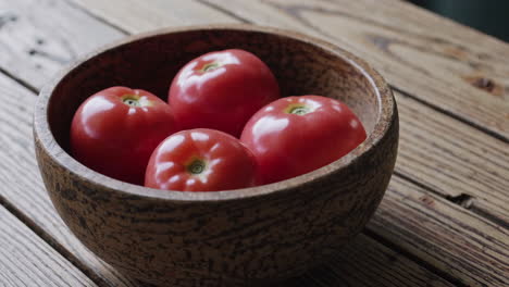 four fresh red tomatoes in a wooden bowl