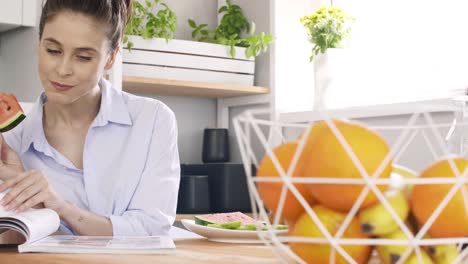 mujer leyendo un libro y comiendo una sandía en casa