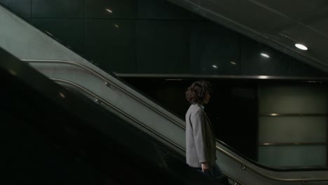 woman walking up escalator in a modern metro station