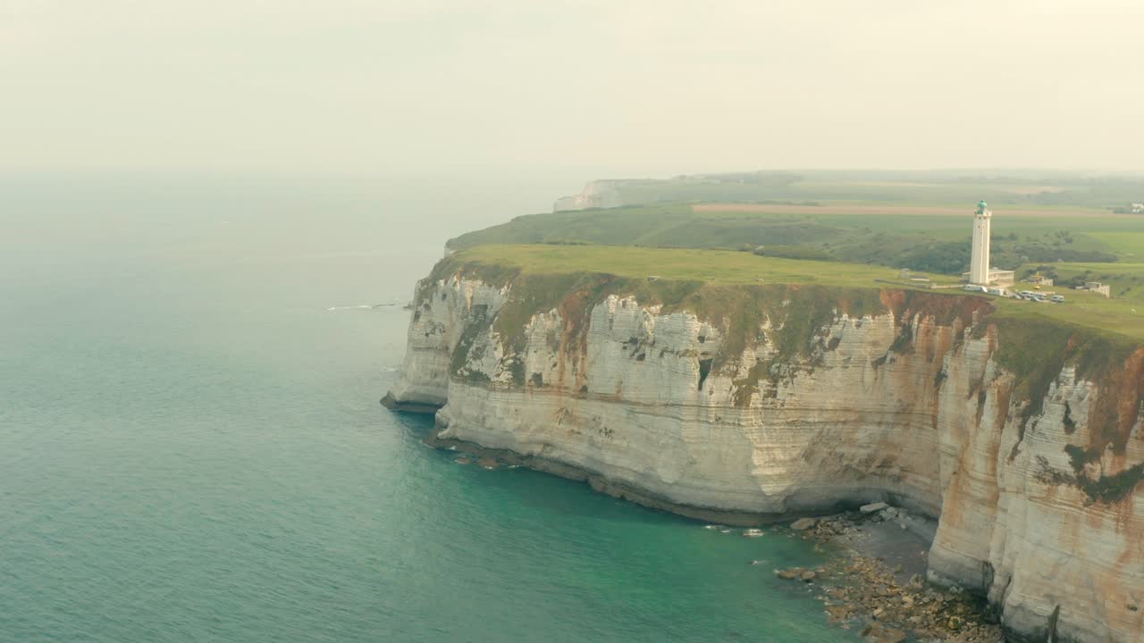 An aerial shot of an old lighthouse on the white cliffs of the coast in France
