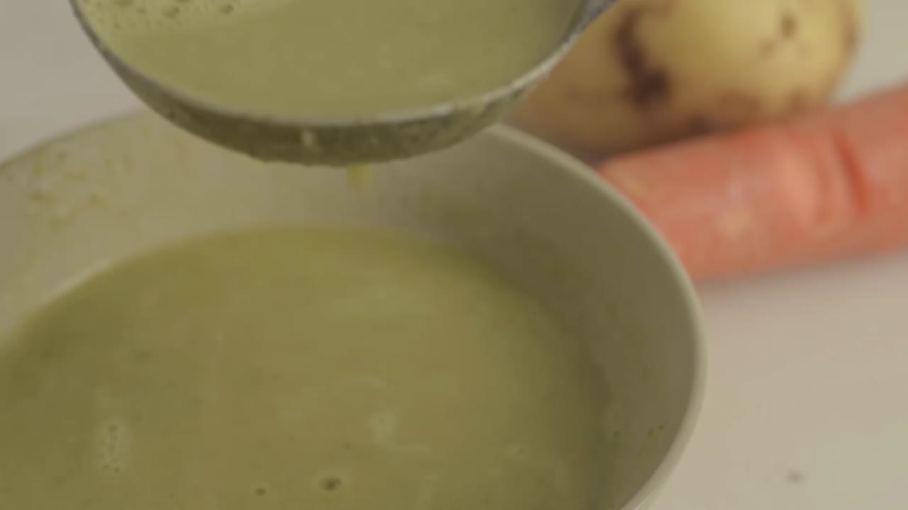 Pouring healthy vegetable soup into a bowl with a ladle close up