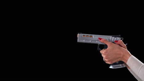mujer apuntando con una gran pistola plateada, amartillando y disparando sobre fondo negro
