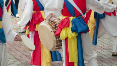 primer plano del grupo de rendimiento de pungmul de jugadores caminando y golpeando tambores durante el festival de ginseng insam de geumsan en geumsan-gun, corea del sur