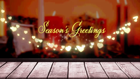 seasons greetings text and glowing yellow heart shaped fairy light decoration over wooden plank