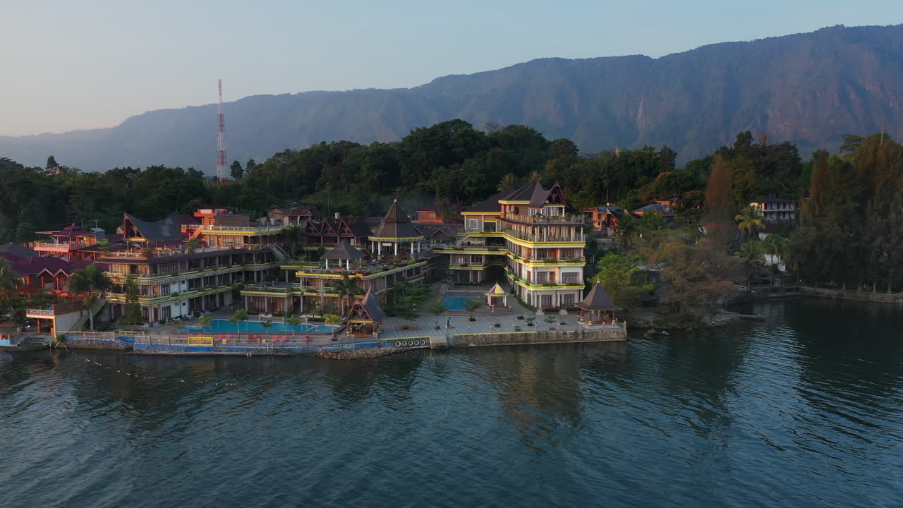 인도네시아 북부 수마트라 사모시르 섬의 토바 호수 가장자리에 있는 사모시르 섬 절벽과 리조트의 풀백 드론 영상