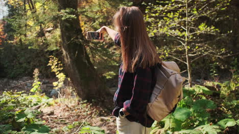 mujer tomando una foto en un bosque