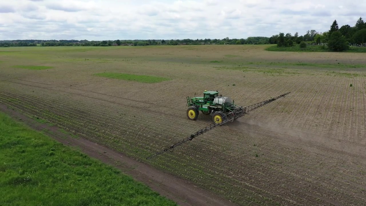 Trattore Agricolo Irroratore al Lavoro in un Grande Campo Agricolo