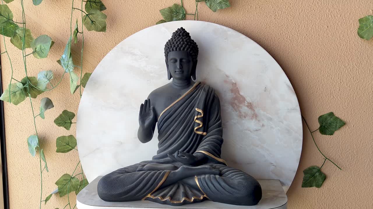 Beautiful 4K footage of peaceful Buddha statue with elegant gold accents, set against marble backdrop with greenery. Ideal for meditation, Zen decor, mindfulness, relaxation and spiritual ambiance.