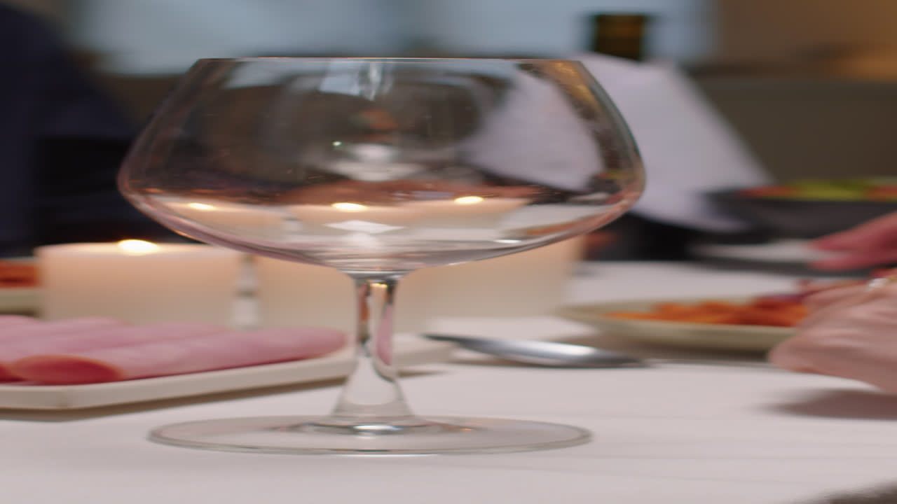 Uomo irriconoscibile versa del vino nel bicchiere della moglie durante la cena