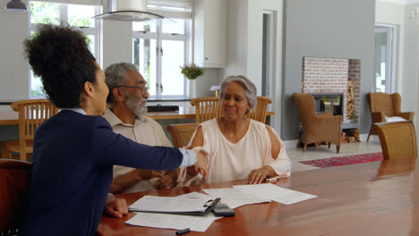 Mixed-race-female-real-estate-agent-discussing-over-property-with-senior-couple-at-home-4k